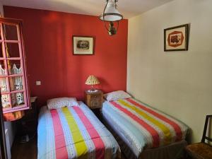 two beds in a room with red walls at Pavillon in Beaufay