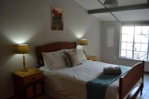 a bedroom with a bed and two lamps and a window at Winecellar Cave, on wine farm & where lions roar! in Stellenbosch