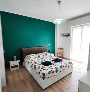 una camera da letto con un letto con una parete verde di Renesmee Beach Apartment a Pietra Ligure