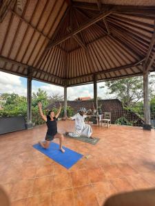 two people are doing yoga in a pavilion at Bali Telaga Hati Yoga Healing And Retreat Center Hostel in Sanur