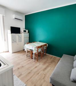 un soggiorno con tavolo e parete verde di Renesmee Beach Apartment a Pietra Ligure