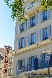 a large white building with blue windows and a street light at Hôtel & Appartements Monsigny in Nice