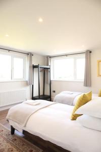 two beds in a white room with two windows at Stone Gate lodge with Private Hot Tub in Boardmills