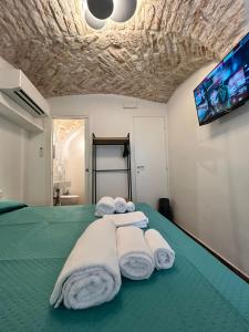a bedroom with a bed with towels and a flat screen tv at HOME 5 - Alcova in Putignano +19 photos