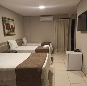 a hotel room with three beds and a television at Ilhabela Park Hotel in Brasília +80 photos
