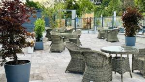 a patio with wicker chairs and tables and trees at Domaine du parc in Grandvillers