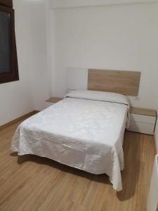 a white bed in a room with a wooden floor at Sol in Cangas de Morrazo