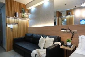 a living room with a black leather couch and a mirror at Staycation near Mall of Asia, Condotel with King Bed in Manila