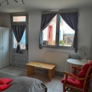 a living room with a table and two windows at Gîte à la ferme avec piscine in Bernadets-Debat