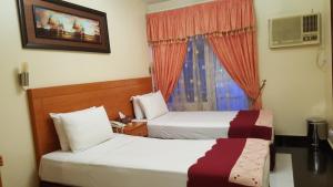 ドバイにあるAl Ahrar Hotelのベッド2台と窓が備わるホテルルームです。