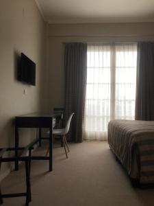 a hotel room with a desk and a bed and a window at Gran Hotel Azul in Azul