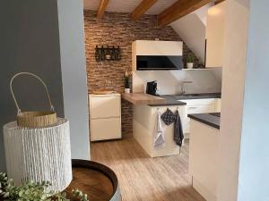 a kitchen with white cabinets and a brick wall at Ferienwohnung Weingut Sturm in Buergstadt
