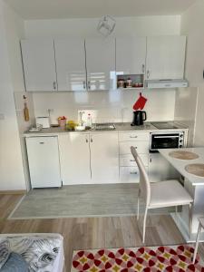a kitchen with white cabinets and a table and a chair at Apartman Nana in Banja Koviljača