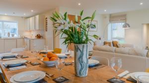 a dining room table with a vase of flowers on it at Songthrush in Somerford Keynes +16 photos