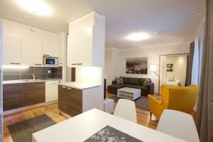 a kitchen and living room with a table and yellow chairs at Kotimaailma Apartments Rovaniemi in Rovaniemi