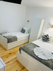 two beds in a room with white walls and wood floors at Apartamento Alfama - Lisbon in Lisbon