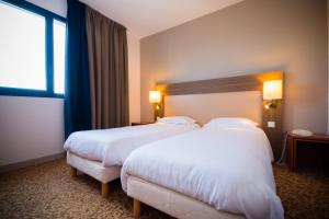 a hotel room with two beds and a window at Brit Hotel Saint Malo – Le Transat in Saint Malo
