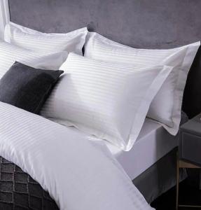 een wit bed met witte lakens en kussens bij Lora apartment,free private parking, self check in in Como