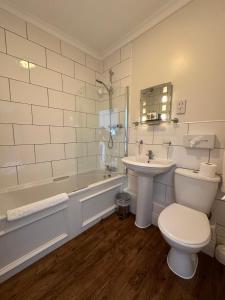 a bathroom with a tub and a toilet and a sink at The White Hart Hotel in Welwyn +44 photos
