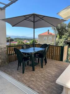 ein Tisch und Stühle mit einem Sonnenschirm auf einem Deck in der Unterkunft Casa Da Serra in Oliveira de Frades