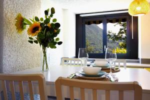 a dining room table with a vase of sunflowers at La Castignola con vista lago di Lugano e giardino condiviso in Lugano