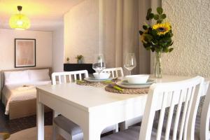 a white dining room table with a vase of flowers on it at La Castignola con vista lago di Lugano e giardino condiviso in Lugano