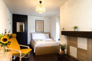 a hotel room with a bed and a yellow chair at La Castignola con vista lago di Lugano e giardino condiviso in Lugano
