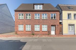 Una casa de ladrillo con ventanas blancas en una calle. en Onkel Theodor, en Husum 5 fotos más