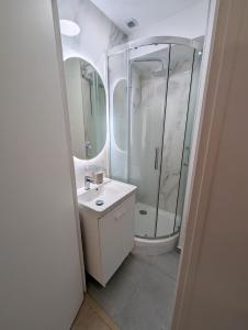 a white bathroom with a shower and a sink at Studio cosy tout équipé proche de Genève in Viry