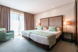 a hotel room with a large bed and a chair at Hotel Dom Goncalo & Spa in Fátima