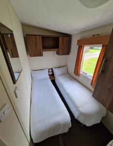 due letti in una piccola stanza con una finestra di Modern 2017 model Delta Sienna static caravan in Clarach Bay ad Aberystwyth Altre 37 foto