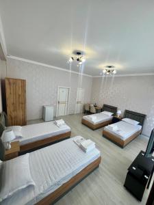a room with three beds and a table and a room with at Best Ali Samira new hotel in Bukhara +71 photos