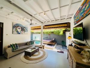 a living room with a couch and a tv at Tiga Kelapa Villa by Smart Digital in Legian