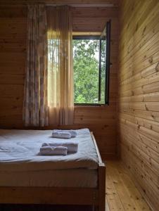 a bed in a wooden room with a window at Guest House Brili in Ghebi in Ghebi