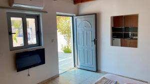 a room with a door and a tv and a kitchen at Iris Studios in Archangelos