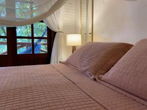 a bedroom with a pink bed with a window at Pousada Vila Serrano in Lençóis
