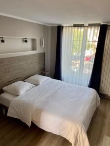a bedroom with a large white bed and a window at Le Relais De La Poste in Pithiviers