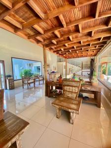 a living room with wooden ceilings and tables and chairs at Penedo House Pousada in Penedo