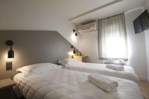 a bedroom with two beds with towels on them at Brit Hotel Essentiel Arverne - Clermont-Ferrand Sud in Aubière