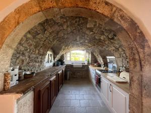 a large kitchen with an archway in a stone wall at La maison Novalia in La Rouquette