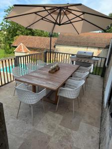 a wooden table and chairs with an umbrella on a patio at La maison Novalia in La Rouquette +4 photos