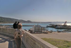 a woman standing on a wall looking at the water at Maison de vacances vue sur la mer in Mazer +4 photos