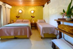 two beds in a room with yellow walls at Pousada Vila Serrano in Lençóis