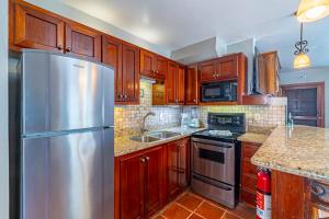 a kitchen with wooden cabinets and a stainless steel refrigerator at Tradewinds Paradise Villas in San Pedro
