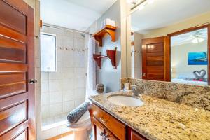 a bathroom with a sink and a toilet and a mirror at Tradewinds Paradise Villas in San Pedro