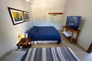 a bedroom with a blue bed and a flat screen tv at Linda Casa C/ Vista pro Mar na Praia Grande em Paraty in Paraty