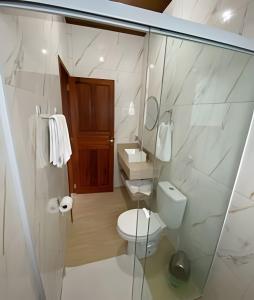 a white bathroom with a toilet and a sink at Linda Casa C/ Vista pro Mar na Praia Grande em Paraty in Paraty