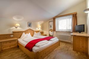 a bedroom with a large bed with a red blanket at Residence Angelika in Corvara in Badia