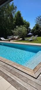 a large blue swimming pool with a wooden deck at Loft de jardin le 8 in Locminé