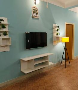 a living room with a television on a blue wall at Flickstays Blossom in Bangalore